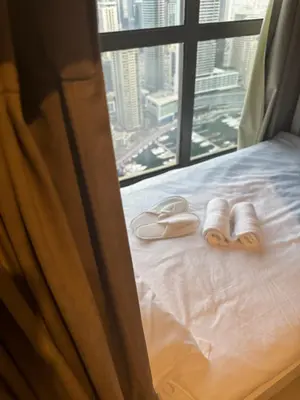 a pair of slippers on a bed in front of a window at Best view homes in Dubai