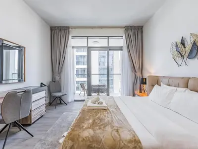 a bedroom with a large bed and a desk and window at Modern Retreat with Balcony and Burj Khalifa View in Dubai