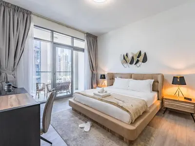 a bedroom with a large bed with a desk and a balcony at Modern Retreat with Balcony and Burj Khalifa View in Dubai