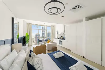 a living room with a white bed and a kitchen at Silkhaus Comfy Studio in Liberty House DIFC Heart in Dubai