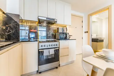 a kitchen with white cabinets and a stove at Community View 1BR with Balcony Near Downtown Dubai, Binghatti Avenue, Al Jaddaf by Deluxe Holiday Homes in Dubai