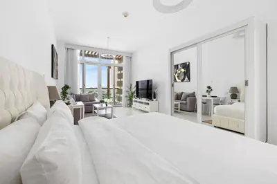 a white bedroom with a large bed and a living room at Studio Palm Views West, Palm Jumeirah in Dubai