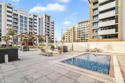 an apartment patio with a swimming pool and buildings at GuestReady - Riviera Studio | Burj Khalifa view in Dubai