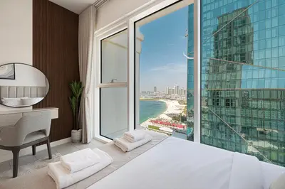 a bedroom with a bed and a desk and a large window at La Vie in JBR! Private Beach! Excellent Apartments! in Dubai