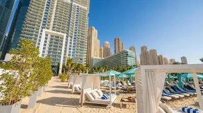 a beach with chairs and umbrellas and buildings at La Vie in JBR! Private Beach! Excellent Apartments! in Dubai