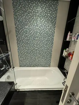 a bath tub in a bathroom with a tile wall at Bright and Airy 2BR Bay Retreat in Dubai