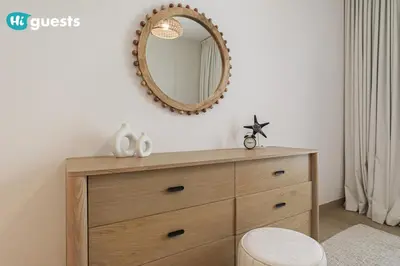 a wooden dresser with a mirror on a wall at HiGuest - Stylish 1BR Apartment in La Mer in Dubai