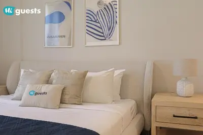 a bed with white pillows and pictures on the wall at HiGuest - Stylish 1BR Apartment in La Mer in Dubai