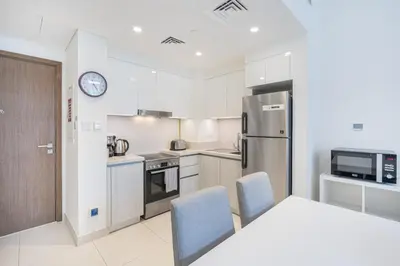 a kitchen with a table and chairs and a refrigerator at Premium Home in Park Point Near Dubai Hills Mall in Dubai