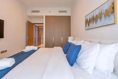 a bedroom with a large white bed with blue pillows at Downtown Luxury 2BR - Full Burj Khalifa & Fountain Views - 5 Minutes Walk to Dubai Mall in Dubai