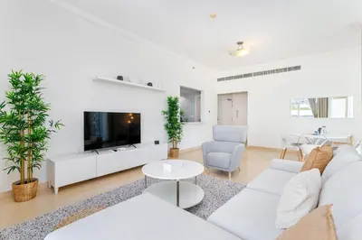 a living room with white furniture and a flat screen tv at Stylish 1-Bedroom with Stunning Marina Views at Dorra Bay in Dubai