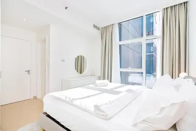 a white bedroom with a large bed and a window at Stylish 1-Bedroom with Stunning Marina Views at Dorra Bay in Dubai