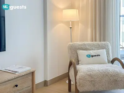 a chair with a pillow on it next to a desk at HiGuest - Elegant 1BR Oasis in La Mer in Dubai