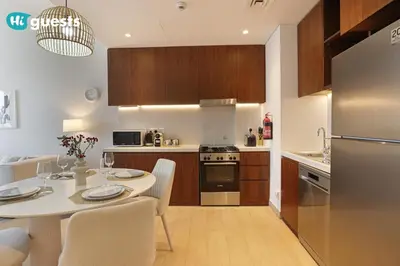 a kitchen with a table with chairs and a refrigerator at HiGuest - Elegant 1BR Oasis in La Mer in Dubai
