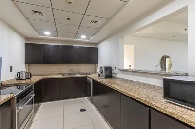 a large kitchen with brown cabinets and a large mirror at Balqis I Renovated 3BDR with 1 maid room I Palm Jumeirah in Dubai