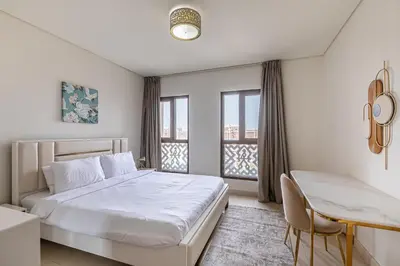 a white bedroom with a bed and a table and chairs at Balqis I Renovated 3BDR with 1 maid room I Palm Jumeirah in Dubai