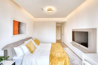 a bedroom with a white bed and a flat screen tv at Classic BNB - Ahad Large 1BR for 4 in Dubai
