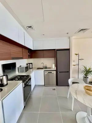 a large kitchen with white appliances and a table at Creek edge,1 bedroom apartment, creek Harbour, high Floor in Dubai