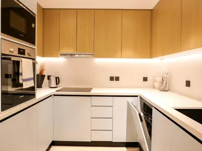 a kitchen with white counters and wooden cabinets at Fresh 3BR Apartment in 5-star Resort in Dubai