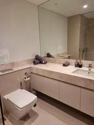 a bathroom with a toilet and a sink and a mirror at Luxury 2 Bedroom Act 1 Apartment in Dubai