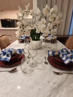 a table with plates and glasses and a vase of flowers at Luxury 2 Bedroom Act 1 Apartment in Dubai