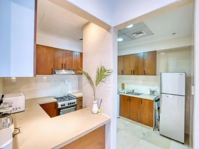 a kitchen with wooden cabinets and a white refrigerator at Classic Orra Marina-1BR in Dubai