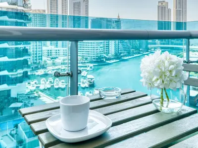 a table with a coffee cup and flowers on a balcony at Classic Orra Marina-1BR in Dubai