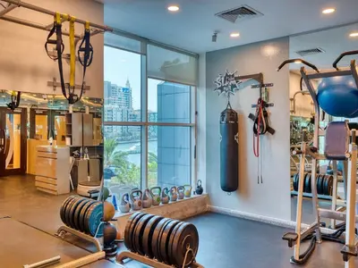 a gym with several treadmills and a large window at Classic Orra Marina-1BR in Dubai