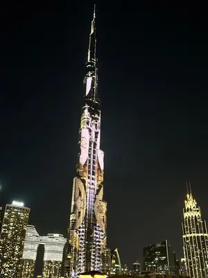 a tall building is lit up at night at Dubai mall Aparment in Dubai