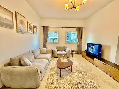 a living room with a couch and a tv at Cozy Family-Friendly 2BR in JVT in Dubai