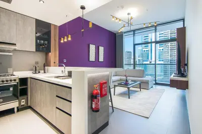 a kitchen with purple walls and a living room at MBL Royal, JLT -One Bedroom with Lake View in Dubai
