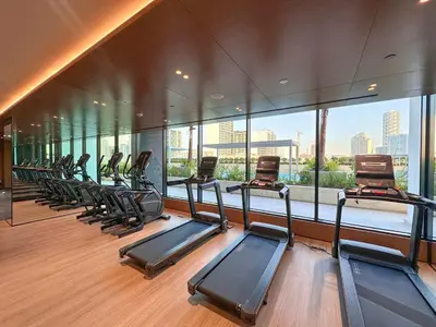 a gym with a row of treadmills and windows at AWS Holiday Homes - Perfect Dubai Stay! in Dubai