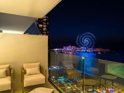 a room with two chairs and a ferris wheel at night at 1BR Suite FIVE LUXE - Pool & Beach view - Private Hot Tub - Ventura Stays in Dubai