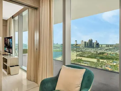 a living room with a green chair and a large window at 1BR Suite FIVE LUXE - Pool & Beach view - Private Hot Tub - Ventura Stays in Dubai