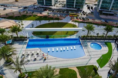 an overhead view of a resort with a swimming pool at Fully Furnished Elegant Studio Apartment Close by Dubai Science Park, Dubai Miracle Garden, Butterfly Garden and Dubai Hills Mall in Dubai