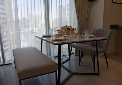 a dining room table with chairs and a table with flowers on it at Bespoke Holiday Homes - Luxury 1BR in High Floor with Stunning Canal Views in Dubai