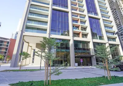 a tall building with trees in front of it at Bespoke Holiday Homes - Luxury 1BR in High Floor with Stunning Canal Views in Dubai