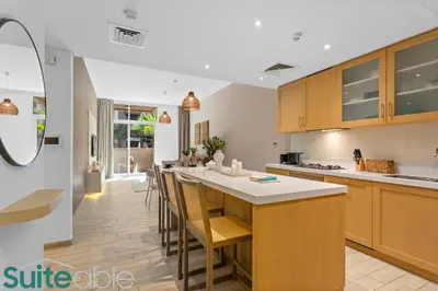 a kitchen with wooden cabinets and a bar with stools at Serene 1 Bedroom apartment in Belgravia - JVC in Dubai