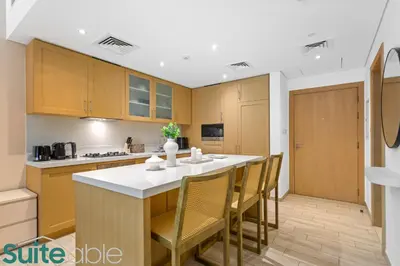 a kitchen with wooden cabinets and a table with chairs at Serene 1 Bedroom apartment in Belgravia - JVC in Dubai