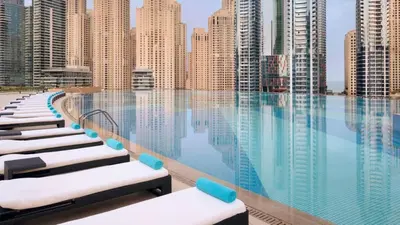 a pool with chaise lounges in front of tall buildings at JW Marriott Stylish 1BR - Marina View - Direct Dubai Marina Mall Access - Pool & Gym - Free Parking in Dubai
