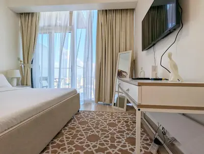 a hotel room with a bed and a desk and window at Fully Furnished Cozy Studio at JVC Dubai, Short Drive to Dubai Marina, JBR, Downtown Dubai in Dubai