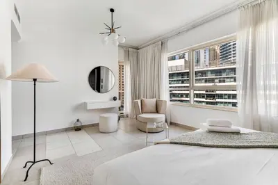 a white bedroom with a bed and a chair at GuestReady - Glamorous stay in Dubai Marina in Dubai