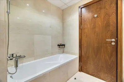 a bathroom with a tub and a wooden door at GuestReady - Glamorous stay in Dubai Marina in Dubai