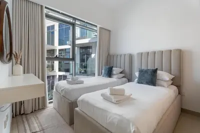 two beds in a room with a large window at GuestReady - Contemporary retreat at Azizi Gardens in Dubai