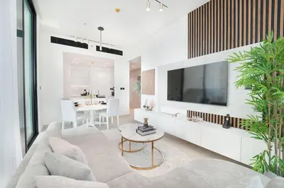a living room with a couch and a tv on a wall at EasyGo- Luxury, Private Pool and Serene Location in Dubai