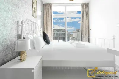 a white bedroom with a bed and a window at Tranquil 3br Townhouse in Damac Hills2 by deleguest in Dubai