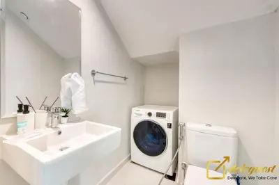 a white bathroom with a washing machine and a sink at Tranquil 3br Townhouse in Damac Hills2 by deleguest in Dubai