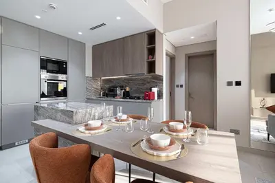 a kitchen with a dining table with chairs and a counter at Modern 1-Bedroom Apartment with Luxurious Amenities in JVC in Dubai