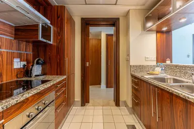 a kitchen with wooden cabinets and a sink at HAVN - 1 Bed in Dubai Marina, 5mins walk to JBR in Dubai