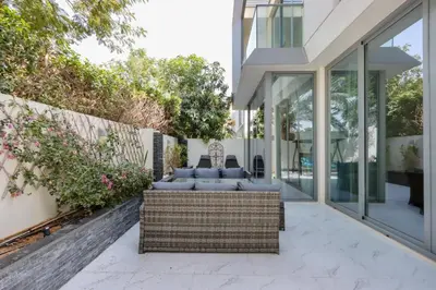 a patio with wicker furniture and glass walls at Livbnb-Tranquil Family Home, 4BR with Maid's Room in Dubai